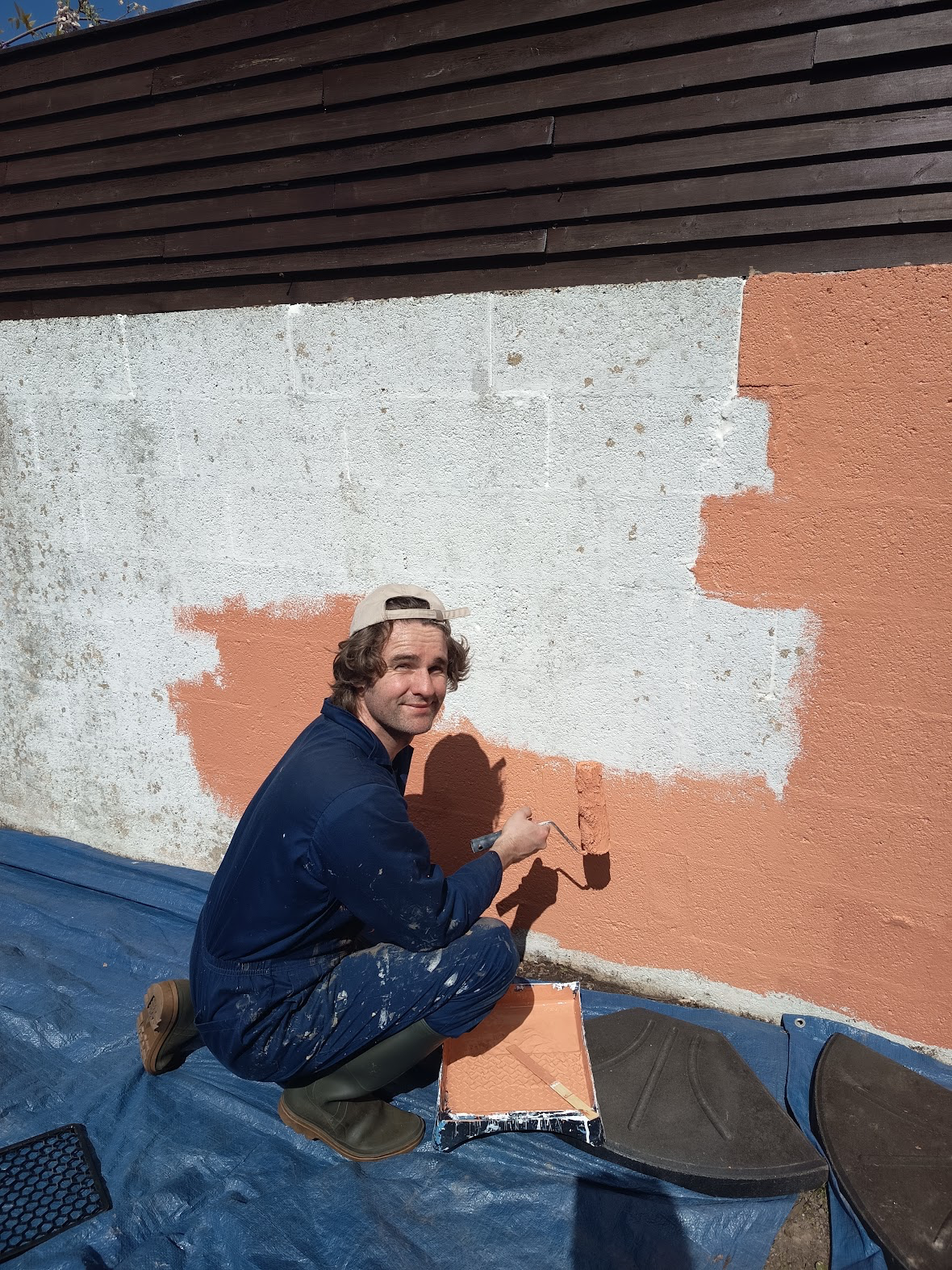 Guillaume peignant le mur extérieur de Sous le Pommier
