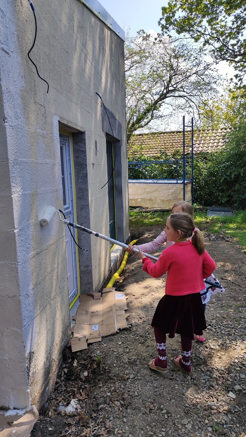 Deux enfants participant à la peinture extérieure de Sous le Pommier