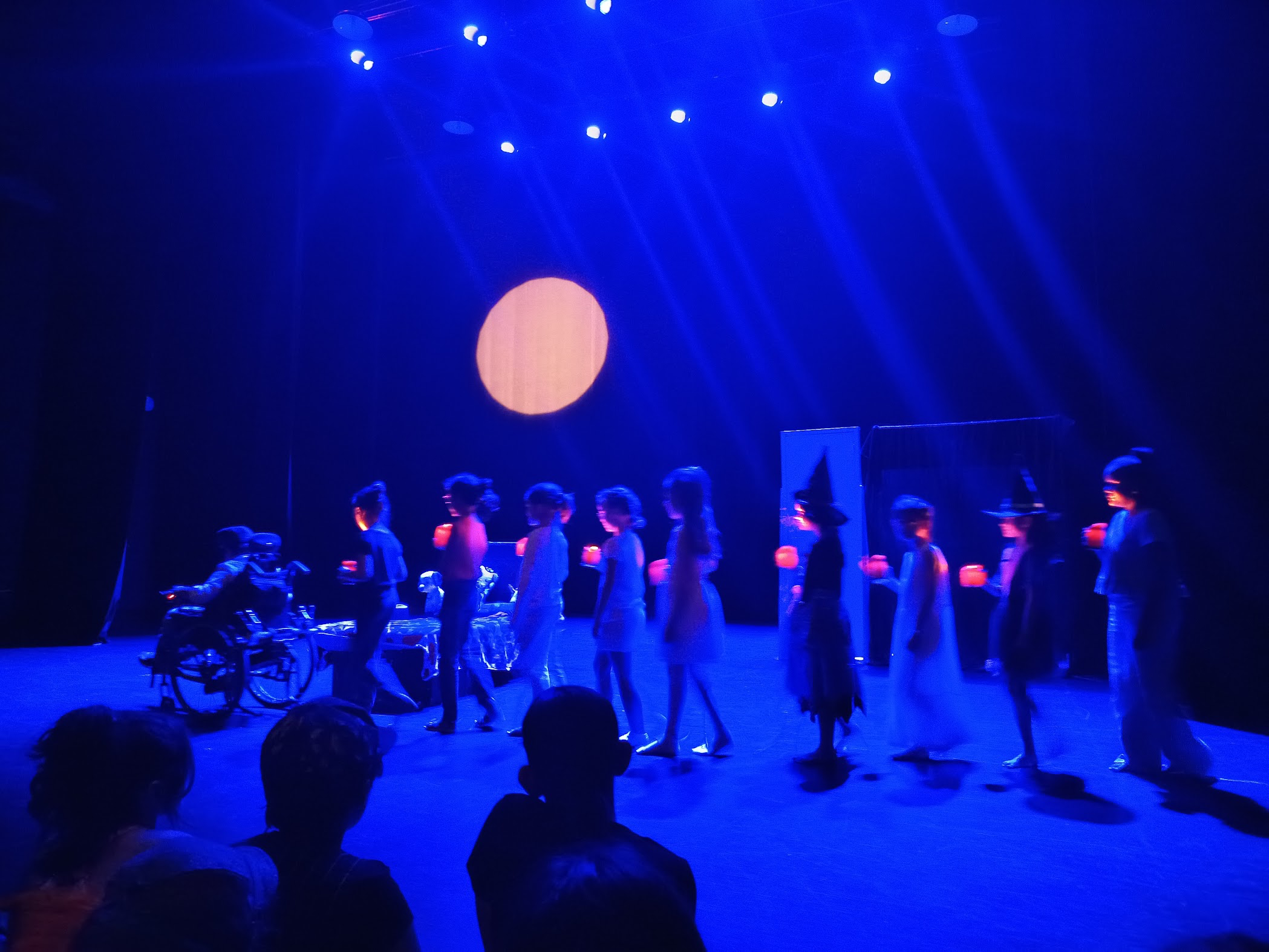 Des enfants jouent sur scène dans une lumière bleue lors d’un spectacle de théâtre